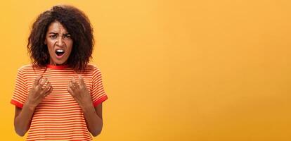 Waist-up shot of woman feeling upset feeling unfair things happened complaining and whining with regret frowning gesturing with palms near breast standing over orange background photo