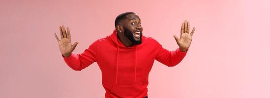 Knock who there. Charming happy funny black bearded guy bending towards camera raised palms move like mime act pressed face glass smiling joyfully fool around playful energized mood photo