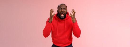 Guy hates subway. Irritated hungry mad bearded african-american man yelling squeez fists frowning grimacing shouting losing temper furiously staring camera go crazy insane, standing pink background photo