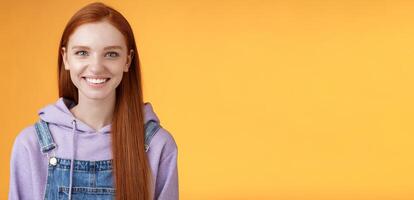 Attractive modern hipster young redhead girl smiling delighted relaxed talking have casual joyful day downtown walking friends wearing purple hoodie overalls, summer vibes, standing orange wall photo