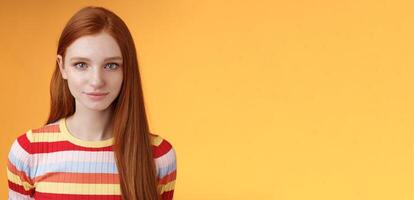 Attractive young sincere redhead girl clean pure perfect skintone smiling modest look camera friendly delighted standing relaxed awaiting gazing silly tenderly, posing orange background photo