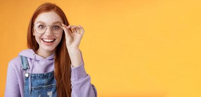 Happy enthusiastic young redhead girl amused find out excellent place celebrate b-day standing joyful excited touch glasses smiling broadly white teeth grinning rejoicing surprised, orange background photo