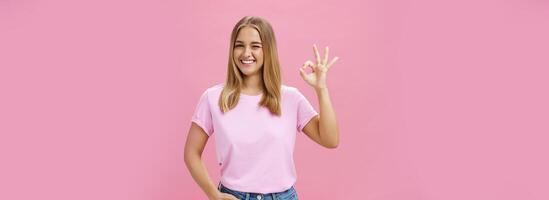 usted lata contar en a mí. retrato de confidente y positivo joven hembra tienda asistente asegurando producto es genial sonriente en general parpadeo a cámara y demostración bueno gesto en me gusta y aprobación foto