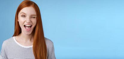 Cheeky good-looking flirty young gorgeous redhead girlfriend winking sassy smiling delighted open mouth hinting have interesting suggestion keep secret standing amused blue background photo