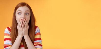 Excited shocked redhead speechless girl like gossiping standing emotional astonished hear amusing story gasping full disbelief cover mouth palm amazed posing orange background impressed photo