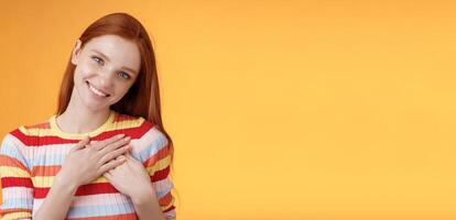 Pleased tender feminine good-looking redhead woman receive compliment confession touch heart feel warmth dearest moment smiling delighted lovely keep love inside soul, standing orange background photo