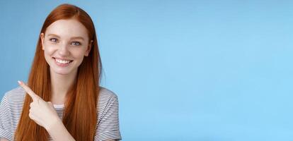 Close-up attractive gentle tender friendly-looking smiling redhead woman show place pointing upper left corner index finger grinning helpful giving choice help find store, standing blue background photo