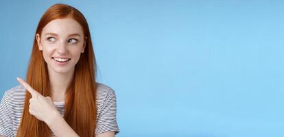 Intrigued good-looking redhead joyful curious girl watching looking upper left corner interested smiling broadly visit cool amusing place explore travelling new country astonished, blue background photo
