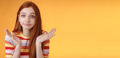 Clueless unbothered young redhead silly european girl 20s shrugging hands spread sideways smirking sorry cannot answer standing unaware confused puzzled give reply, orange background photo