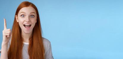 Excited good-looking cheerful ginger girlfriend add idea conversation raise index finger eureka gesture open mouth wide tell suggestion smiling broadly pondering excellent variant, blue background photo