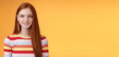 Pleasant friendly-looking confident smart redhead female student aim success smiling self-assured express lucky positive upbeat mood casually hang out orange background listening amusing story photo