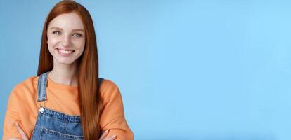 Young stylish confident smiling female redhead freelancer assured job done great grinning satisfied hold hands crossed chest self-assured standing blue background good mood upbeat attitude photo