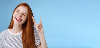 Happy cheerful carefree chilling redhead teenage girl having fun stick tongue close eyes dancing joyfully show rock-n-roll heavy metal sign enjoy party amusing festival music performance photo