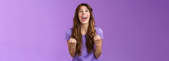 Relieved happy girl thank god awesome achievement celebrate success implore lord grateful fist pump yelling raise head up sky triumphing good news stand purple background joyful positive reaction photo