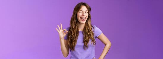 Okay got it. Cheeky flirty girlfriend winking coquettish show alright okay ok sign smiling broadly reassure friend outfit awesome express approval agree good idea stand purple background pleased photo