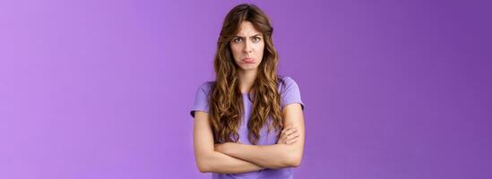 Offended silly timid cute girl sulking pouting lips frowning whining upset cross hands block pose insulted look moody camera disagree acting childish complaining unfair game purple background photo