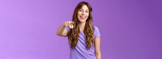 Entertained amused attractive lively girl curly hairstyle laughing happily pointing you finger indicate camera make choice smiling broadly assured believe decision right stand purple background photo