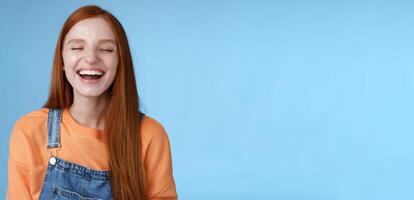 Carefree happy positive lucky redhead girl having fun close eyes smiling optimistic laughing out loud chuckling funny joke listen hilarious stories relaxing hang out friends, blue background photo