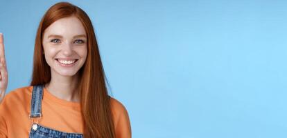 Confident happy charismatic ginger girl blue eyes freckles helpful showing product raising index finger up pointing cool copy space smiling broadly made choice recommend pick, studio background photo