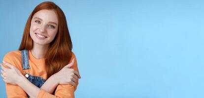 Tender silly redhead girl standing blue background smiling joyfully hugging arms crossed body feel chilly grinning delighted talking boyfriend romantic date asking lend jacket cold summer evening photo