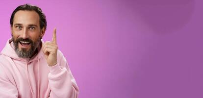 Have great idea listen. Excited energized happy charismatic male bearded guy raising index fingers add suggestion show eureka gesture smiling broadly suggesting perfect plan, purple background photo