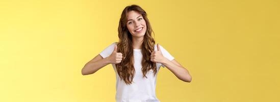 Cheerful enthusiastic young woman support lgbtq pride give thumbs-up tilt head approval like gesture accept perfect choice nodding positive reply recommend excellent service yellow background photo