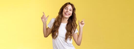 Outgoing cheerful attractive woman curly haircut wear casual white t-shirt dancing party having fun pointing up disco moves having fun smiling broadly enjoy holidays anticipating summer trip photo