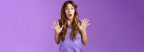 Ambushed shocked girl gasping not expect friend jump out corner raise palms surprised astonished drop jaw open mouth stunned stare camera impressed stupefied purple background photo