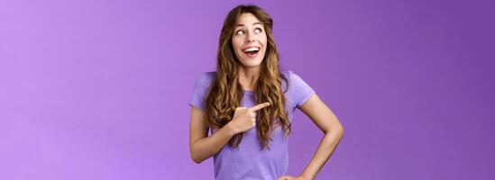 Dreamy wondered impressed cute lively excited positive girl feel happy travel abroad explore new city tourist trip smiling broadly contemplate awesome view look pointing left grinning purple wall photo