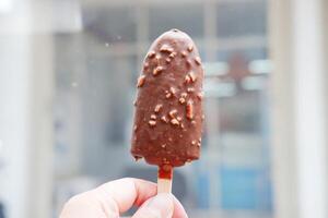 Chocolate ice cream on stick in hand photo