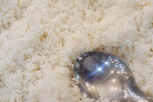 Close up of white rice with spoon in the kitchen. Selective focus photo