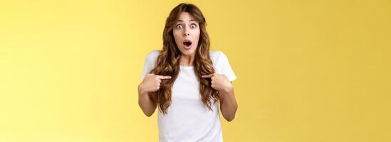 Shocked impressed speechless surprised girl gasping drop jaw pointing herself chest stare camera astonished unexpected promotion being chosen picked winning lottery stand yellow background photo