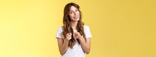 You can do it. Cheerful supportive enthusiastic curly-haired girl makeup artistis encourage girlfriend pointing camera indicating index finger congratulating friend good job yellow background photo