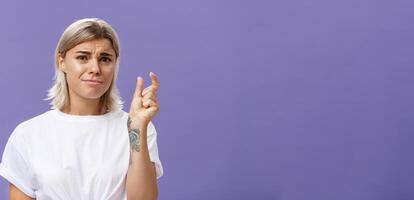 Woman feeling regret lacking small amount of money to afford car. Unhappy displeased good-looking stylish female with tattoos on hands frowning and pursing lips shaping tiny or little object photo