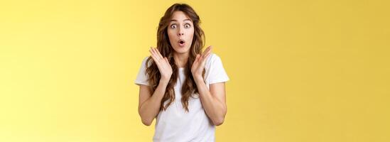 Shocked impressed surprised girl learn interesting pleasant good news clap hands open mouth fold lips wow gasping stare intrigued enthusiastic reaction awesome performance yellow background photo