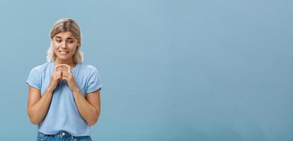 estudio Disparo de inseguro y tímido tonto Novia con rubio pelo apretando dientes mirando tímido abajo y campanario índice dedos desconfiado molesto pedir fuera chico ella gustos terminado azul antecedentes foto