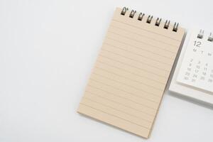 Empty Spiral notepad with brown lined papers and Simple desk calendar for DECEMBER in isolated background. Memo concept with copy space. photo