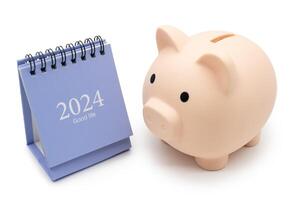 Financial, plan for money saving. Piggy bank and 2024 desk calendar isolated on white background. Goals, Plan, Action, Money Saving, Retirement fund, Pension, Investment and Financial concept. photo