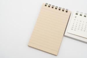 Empty Spiral notepad with brown lined papers and Simple desk calendar for APRIL in isolated background. Memo concept with copy space. photo