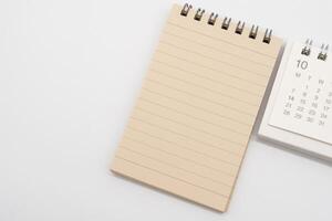 Empty Spiral notepad with brown lined papers and Simple desk calendar for OCTOBER in isolated background. Memo concept with copy space. photo