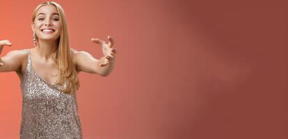 Excited obsessed attractive crazy blond woman in glamour silver dress smiling weird thrilled stretch hands like claws wanna embrace hug ex-boyfriend being clingy, standing red background photo