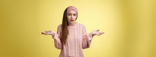 What big deal, why so fuss. Frustrated confused and clueless cute young pretty woman in knitted sweater, headband shrugging in dismay asking question unaware what happening photo