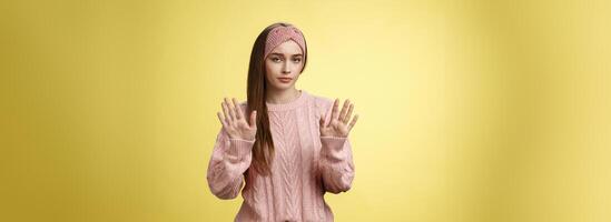 No thanks. Cute unamused picky young girl in knitted sweater, headband showing hold on, slow down, refusal gesture raising palms in rejection being reluctant unimpressed and indifferent to proposal photo