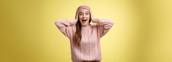 Frustrated girl in panic, screaming grabbing head yelling troubled and scared, staring with buged eyes concerned, feeling nervouse, insecure, shouting frightened and worried against yellow background photo