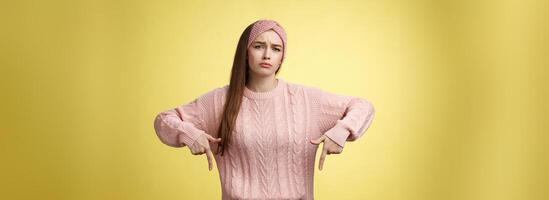 Why me, gosh. Gloomy upset complaining cute glamout young european girl in casual sweater, headband frowning, whining grimacing displeased pointing down, unhappy see lots work over yellow wall photo