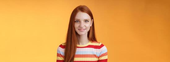 Pleasant friendly-looking confident smart redhead female student aim success smiling self-assured express lucky positive upbeat mood casually hang out orange background listening amusing story photo