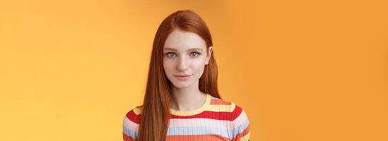 Attractive young sincere redhead girl clean pure perfect skintone smiling modest look camera friendly delighted standing relaxed awaiting gazing silly tenderly, posing orange background photo