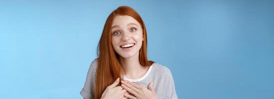 Kind fascinated touched romantic passionate redhead girl blue eyes sighing admiration delight touch heart palms smiling happily grinning grateful thanking friend express gratitude, studio background photo