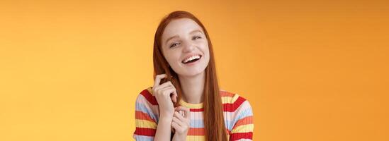 Silly good-looking flirty lively redhead young girl laughing playing coquettish ginger hair strand chuckling amused funny boyfriend jokes having fun awesome romantic date, orange background photo