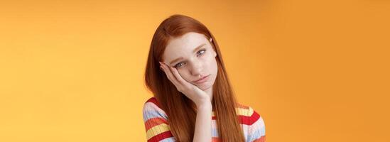 Indifferent careless sleepy redhead silly female student lean palm looking bored uninterested listen lame stories wanna escape standing exhausted lacking interest, posing orange background photo